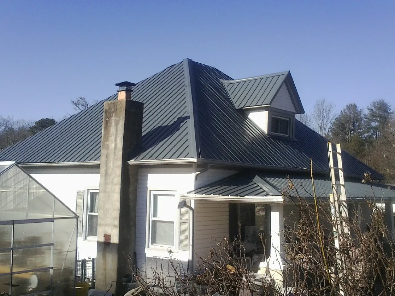Dark blue standing seam metal roof on a white farmhouse with dormer — Slate & Tile Roof Repair by Roofing Brothers in West Haverstraw