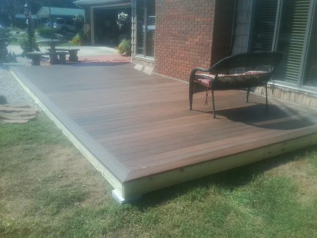 New wood deck and wicker chair beside a brick house in West Haverstraw