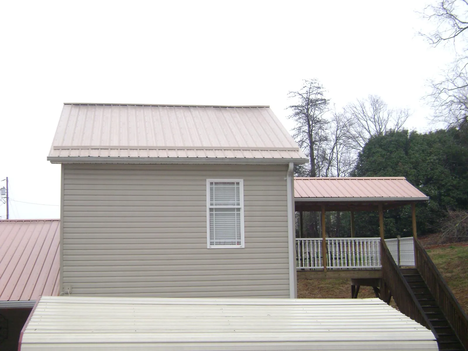 Tan metal roofs on a two story addition and attached porch, from a Roof Replacement job in West Haverstraw