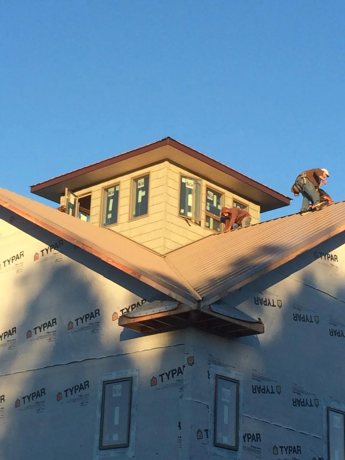 Roofers working around a rooftop cupola on a new metal roof at sunset — Roof Waterproofing in West Haverstraw by Roofing Brothers